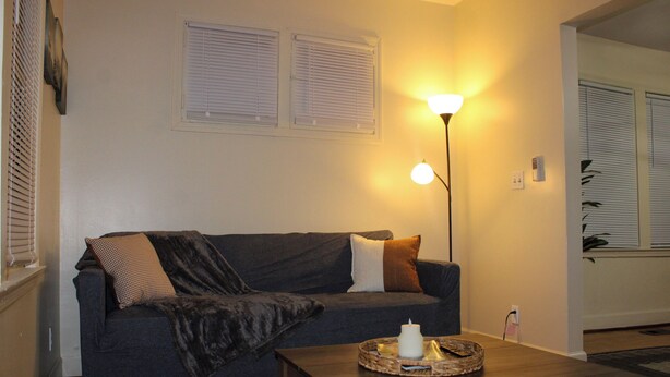 A living room with a dark grey sofa, a wooden coffee table, and a floor lamp. - Downtown Detroit Getaway (Detroit)