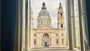 Vista a través de una ventana de un edificio histórico con dos torres destacadas y una cúpula central.
