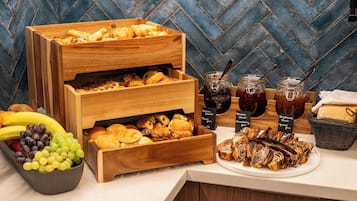 Um buffet de café da manhã com pães, frutas e geleias.