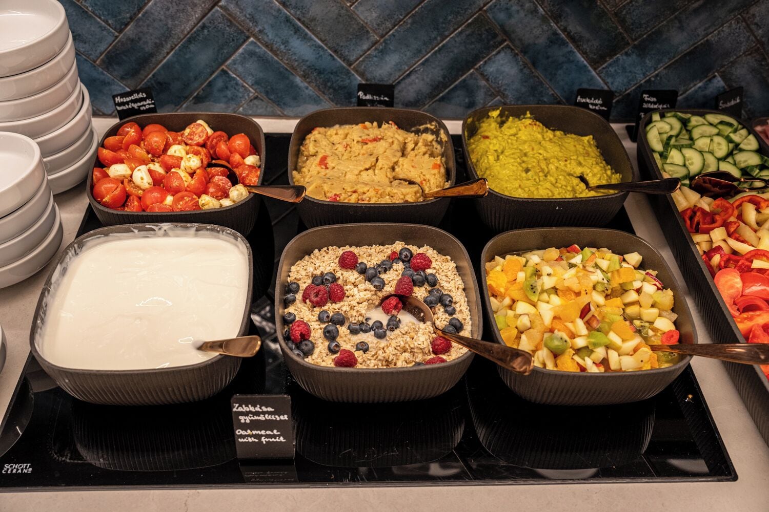 A buffet with various food options including yogurt, granola with berries, and fruit salad.