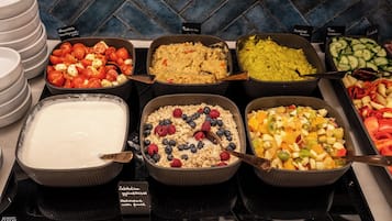 A buffet with various food options including yogurt, granola with berries, and fruit salad.
