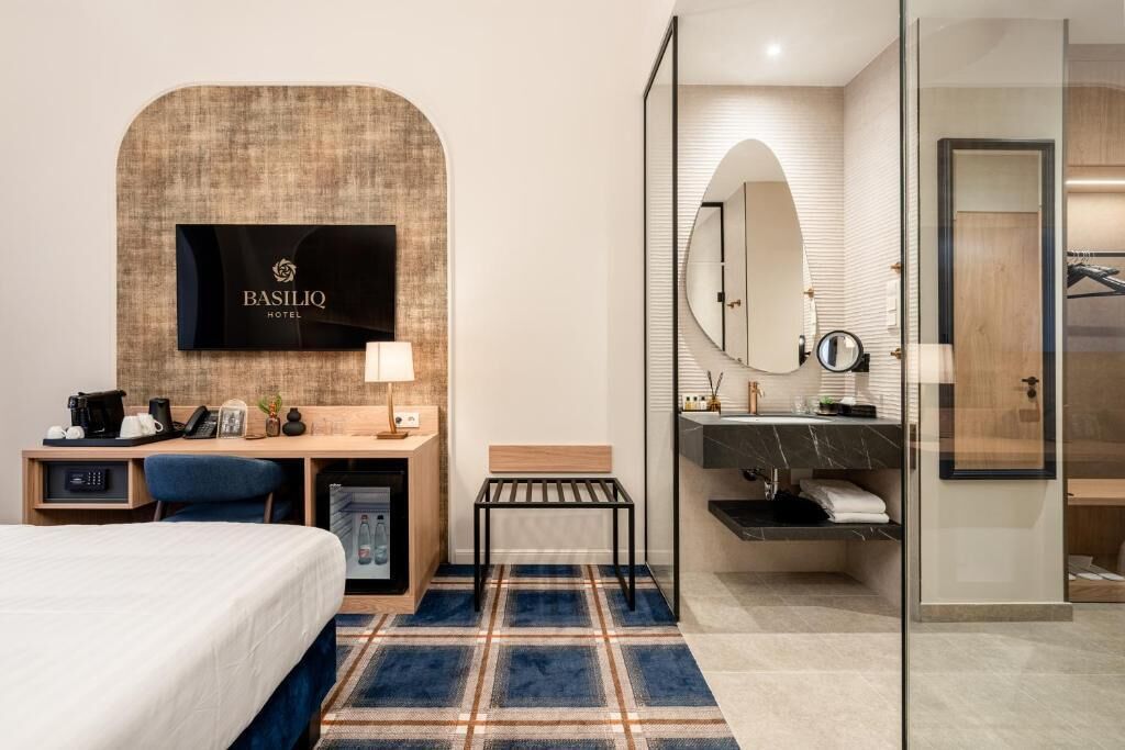 Une chambre d’hôtel équipée d’un lit, d’un bureau et d’un téléviseur fixé au mur.
