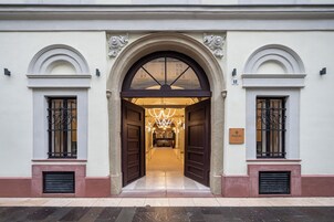 Una entrada imponente con un gran arco, flanqueado por dos ventanas con rejas de hierro forjado.