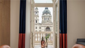 Una habitación con vistas a un edificio histórico, una mesa con una botella y una copa, y dos sillones de cuero.