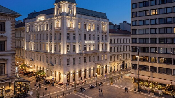 Un edificio histórico con una torre destacada, múltiples ventanas y una entrada central.