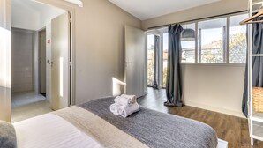 Habitación de hotel moderna con una cama grande, un vestidor amplio y vistas al exterior a través de un ventanal.