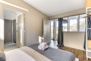 Habitación de hotel moderna con una cama grande, un vestidor amplio y vistas al exterior a través de un ventanal.
