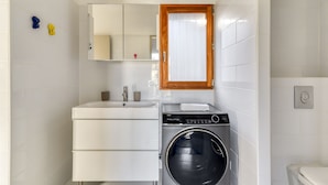 Un baño pequeño con lavabo, espejo y lavadora.