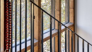 Una escalera con barandillas de madera y vistas a árboles y edificios.