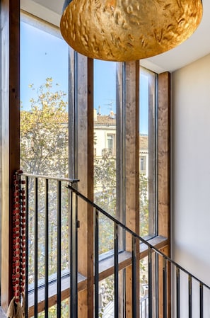 Eine Treppe mit Holzgeländern und Blick auf Bäume und Gebäude vor dem Fenster.