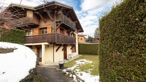 A chalet with a wooden balcony, a snow-covered yard, and a well-maintained hedge. - Cosy Apartment “La Tanière” in Saint-Gervais-les-Bains (Saint-Gervais-les-Bains)