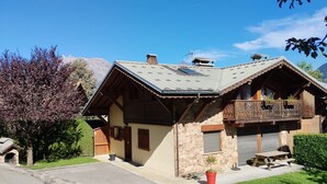 A traditional chalet with a stone facade, wooden balcony, and a small garden area. - Cosy Apartment “La Tanière” in Saint-Gervais-les-Bains (Saint-Gervais-les-Bains)