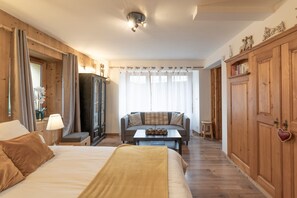 Une chambre d’hôtel avec un lit, un canapé, une petite table avec des fruits, une armoire et une porte ornée d’un motif en forme de cœur.