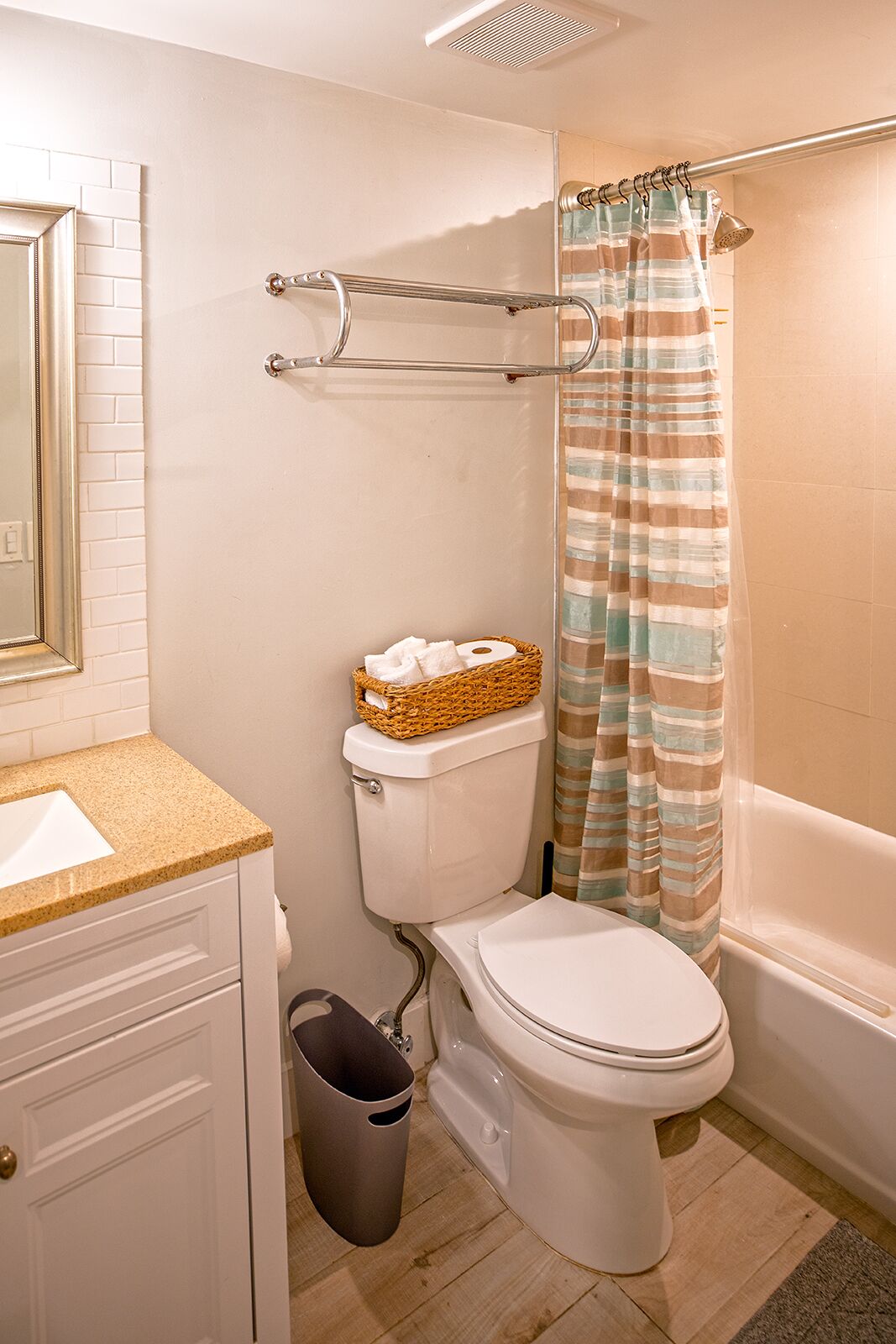 A bathroom with a toilet, a bidet, a sink, a trash bin, and a shower curtain.