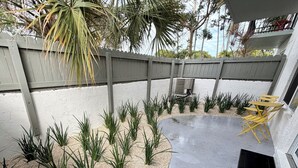 Eine Terrasse mit Betonboden, Holzlattenzaun und einer Sitzecke.