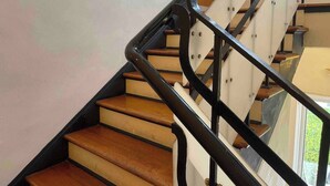 A staircase with wooden steps and black metal railings. - This comfortable 1BR setup features 2 queen beds + a futon, fast WiFi, and the rare perk of FREE parking. <br>A great home base for enjoying Miami, plus stay in the heart of South Beach’s coveted SoFi neighborhood—a short walk to the sand. (Miami Beach)