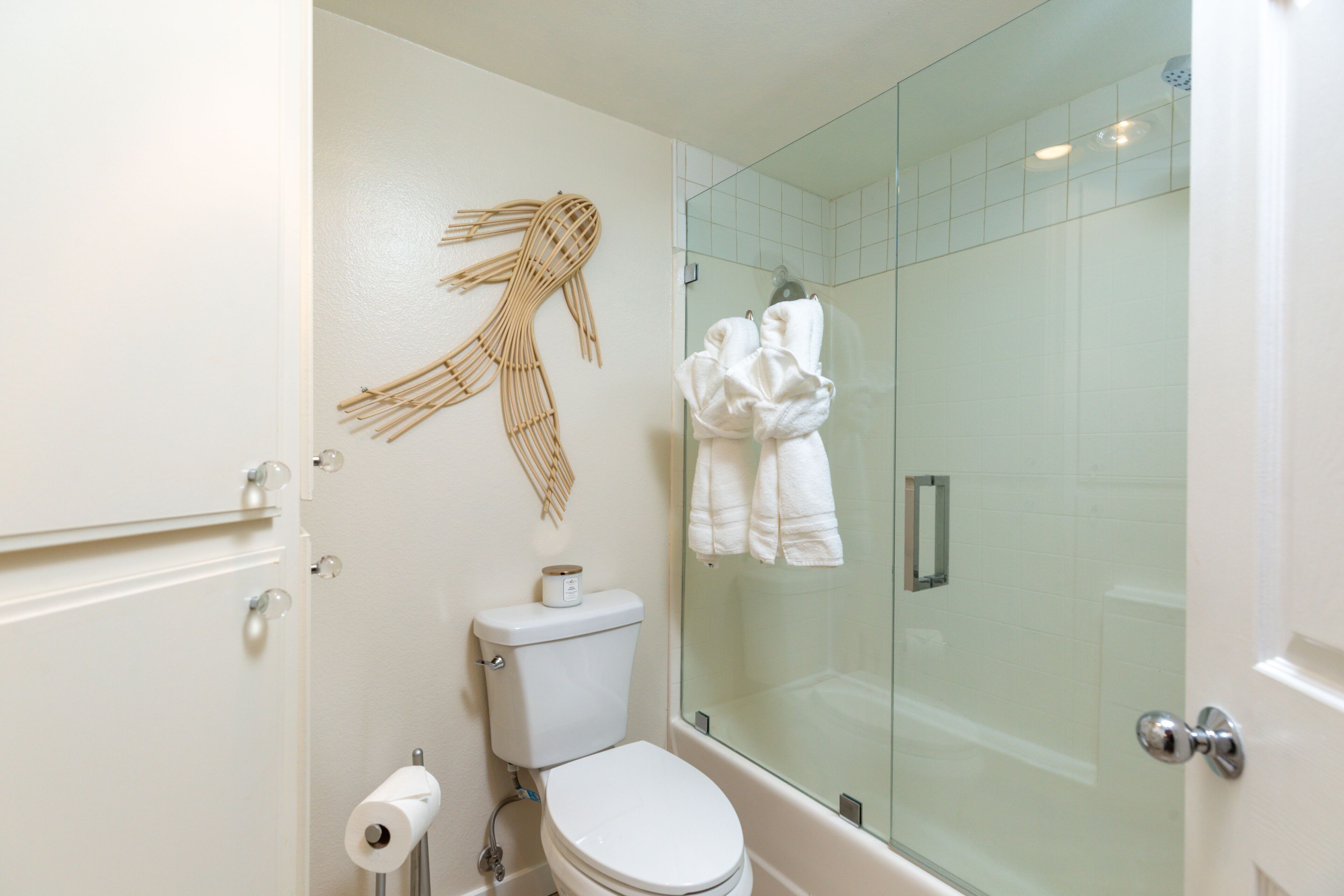 Een badkamer met een toilet, een douchecabine met glazen wanden en een handdoekrek met handdoeken.