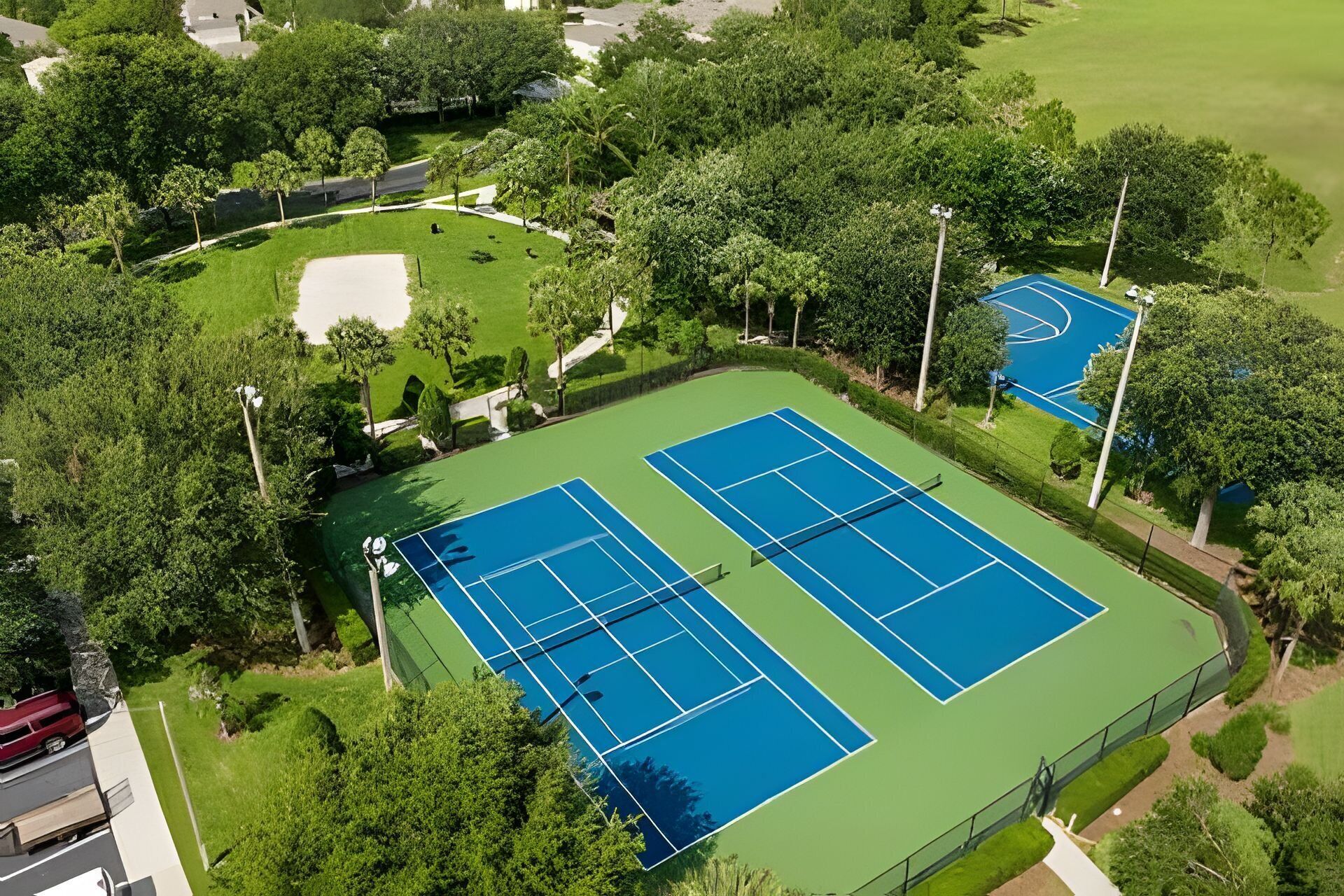 An aerial view of a tennis court complex surrounded by trees and greenery.
