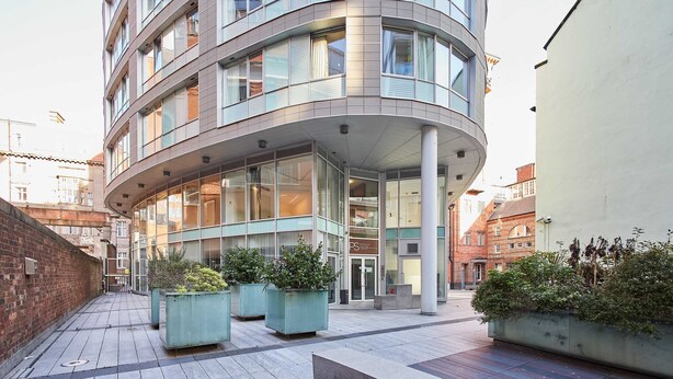 A modern building with a curved facade, large windows, and outdoor seating areas with planters. - Host Stay 408 Hatton Garden (Liverpool)