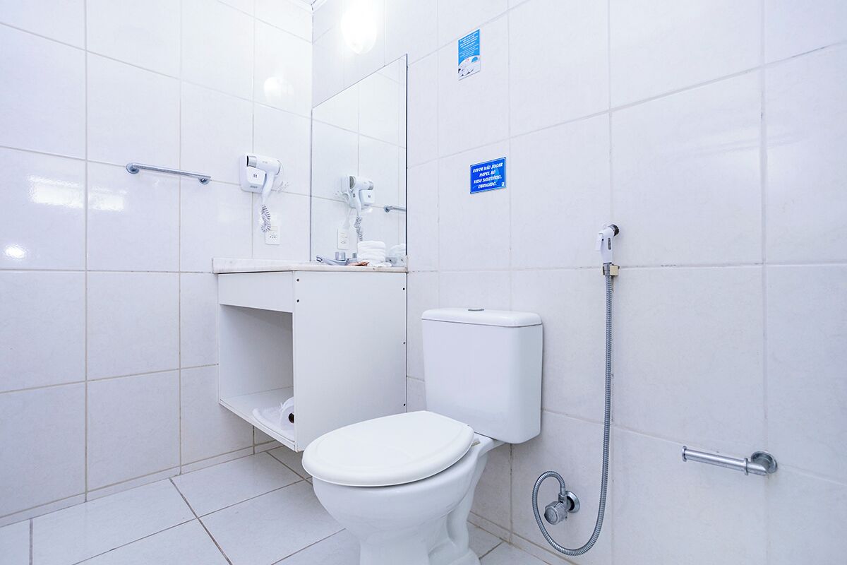 Un baño moderno con inodoro blanco, secamanos y ducha.