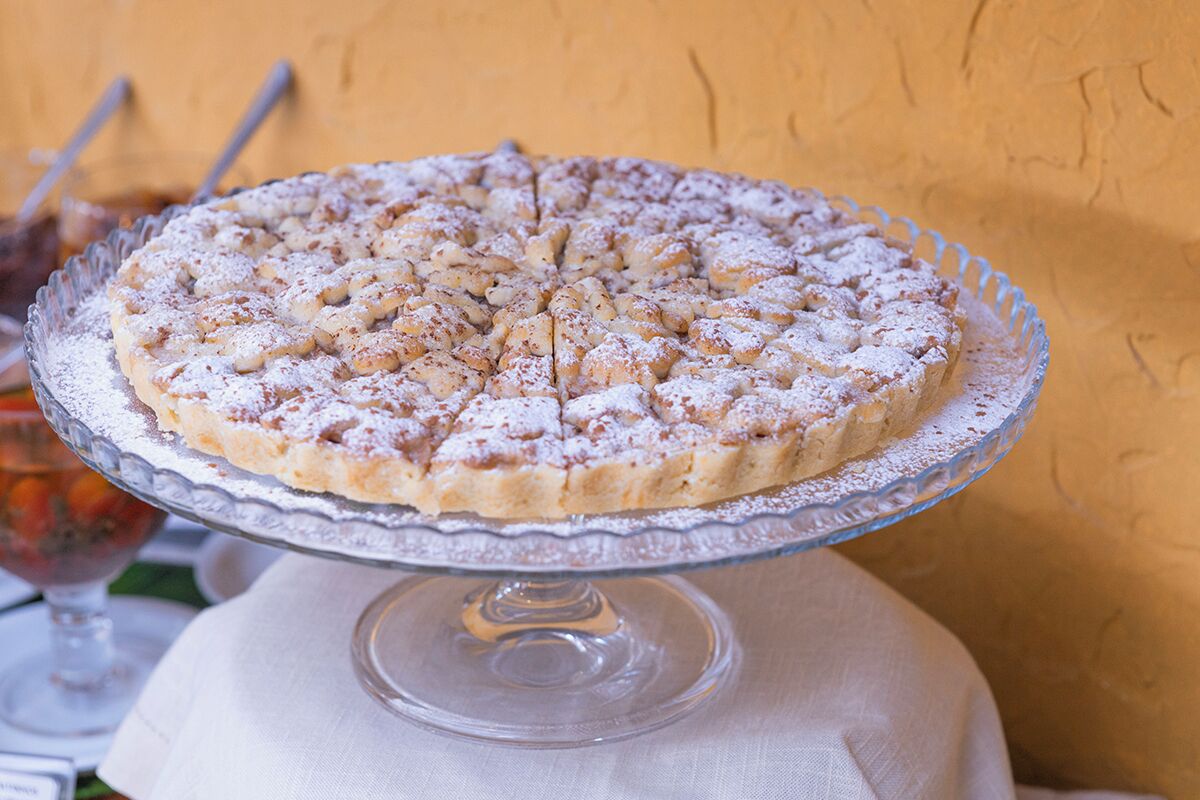 A round cake on a glass cake stand with a dusting of powdered sugar.