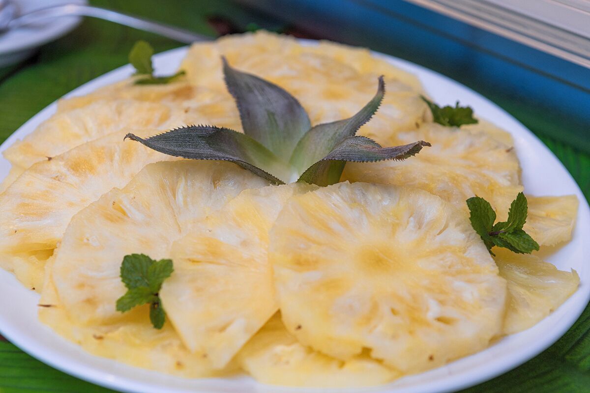 A plate of pineapple slices garnished with mint leaves.