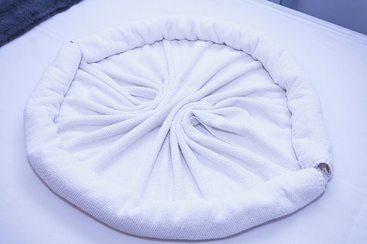 Un objeto redondo y blanco, con textura y un nudo central, sobre una superficie plana.