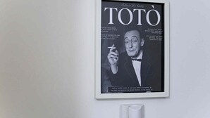 Ein gerahmtes Magazincover von TOTO mit Text und einer Person, die eine Zigarette hält.