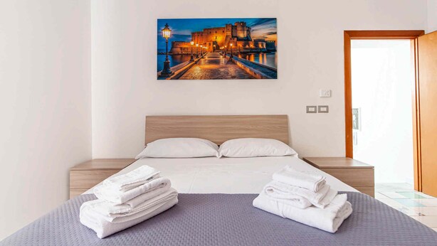 Ein Hotelzimmer mit einem Bett, einem Stadtbildgemälde und Handtüchern auf dem Bett.
