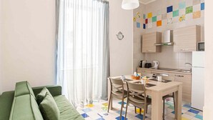 Ein gemütlicher Wohnbereich mit Küchenzeile, Essplatz und einem grünen Sofa.
