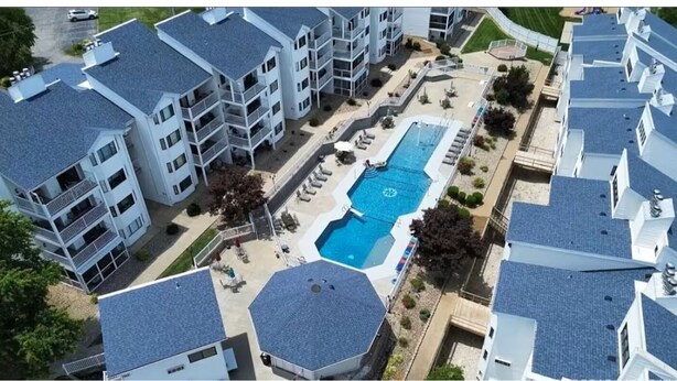 Un edificio residencial de varios pisos con piscina en la azotea y zonas de estar al aire libre.