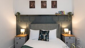 Une chambre à coucher bien aménagée, avec un grand lit, deux tables de chevet et une tête de lit dotée d’une étagère au-dessus.