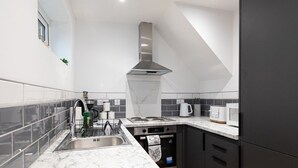 Une cuisine moderne dotée d’un évier en acier inoxydable, d’une cuisinière encastrée et d’une hotte aspirante.