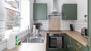 Eine moderne Küche mit grünen Schränken, einer Edelstahlspüle und einem eingebauten Backofen.