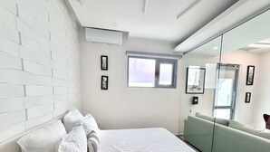 Ein modernes Schlafzimmer mit Bett, großem Fenster und einer Glaswand.