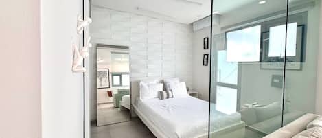 Un dormitorio moderno con cama, un separador de vidrio y vistas a otra habitación.