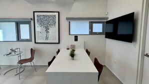 Ein moderner Konferenzraum mit einem langen Tisch, Stühlen, einem Flachbildfernseher und gerahmten Kunstwerken an den Wänden.