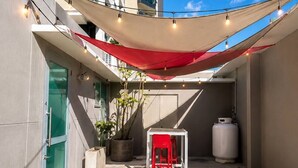 Ein möblierter Außenbereich mit Tisch, Stühlen, einem Blumentopf und einem Warmwasserbereiter.
