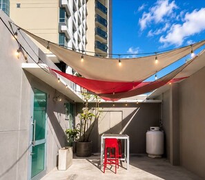 An outdoor patio area with a table and chairs, a potted plant, and a water heater. - Condado Condo Retreat | Private Patio (San Juan)
