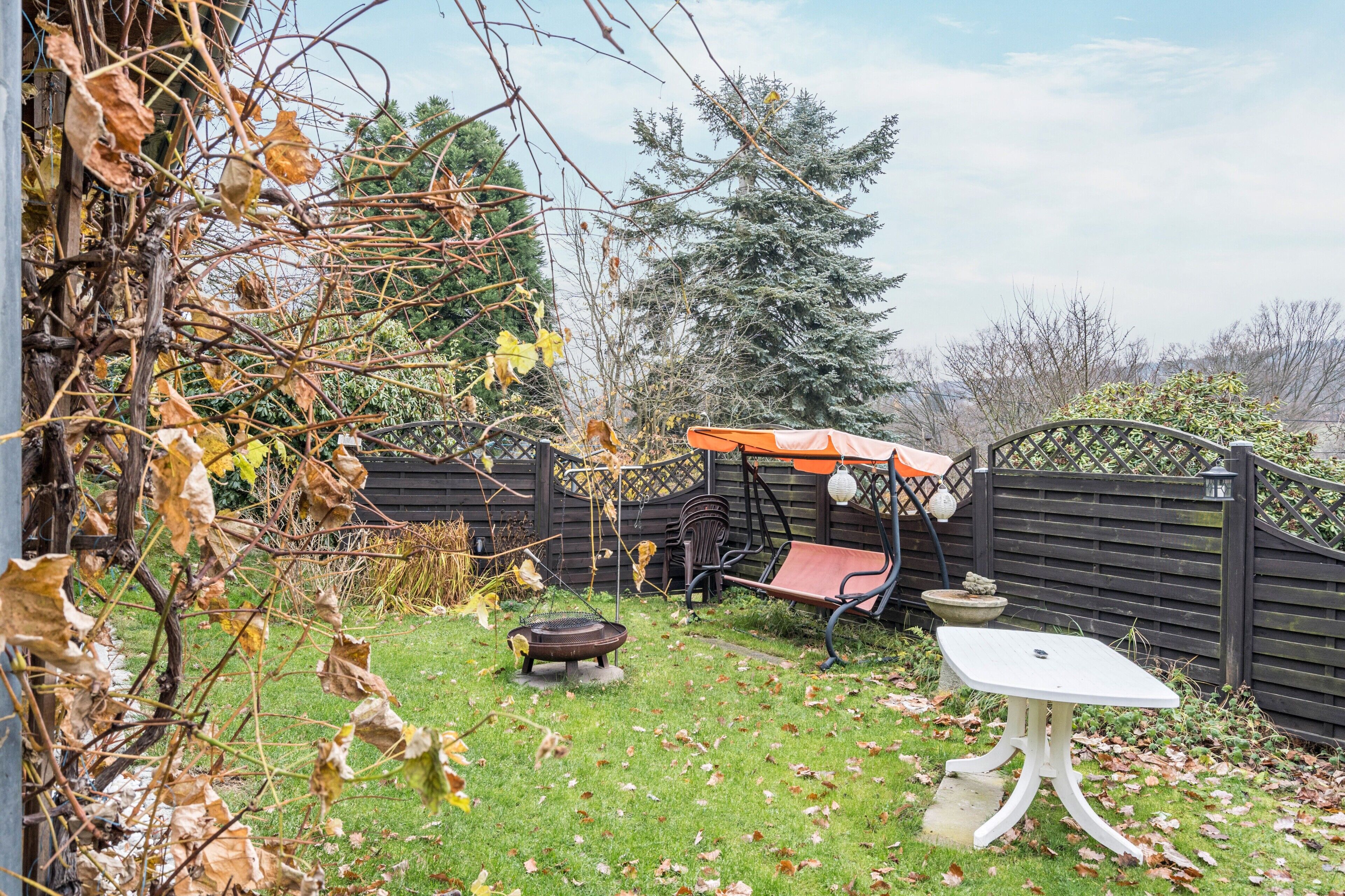 A backyard with a swing set, a table, and a fire pit.