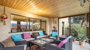 A cozy outdoor seating area with wicker furniture, a glass-top coffee table, and a view of the surrounding landscape. - Apartment "Heidi" with Mountain View, Private Garden and Wi-Fi (Rosenthal-Bielatal)