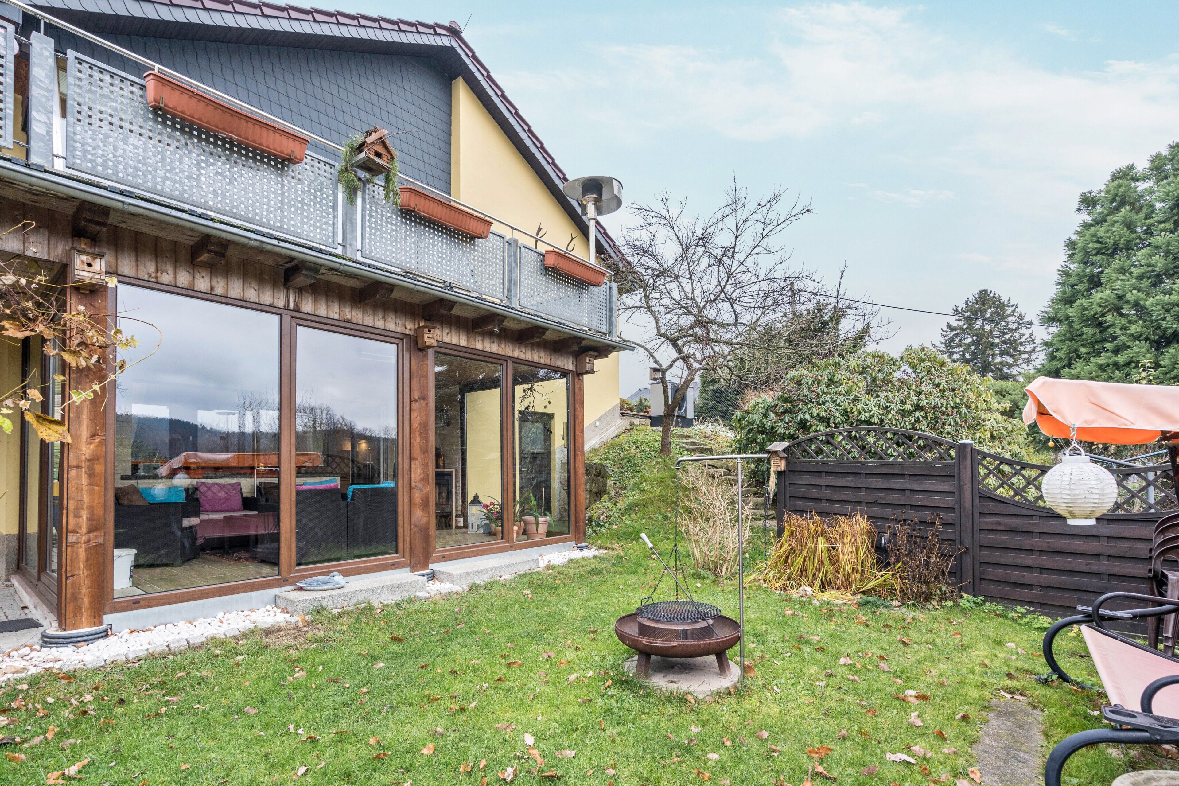 A house with a balcony, a garden, and a patio area.