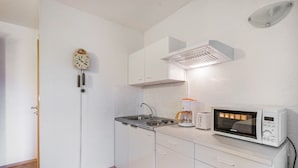 A small kitchen with white cabinets, a sink, a coffee maker, and a microwave. - Apartment "Heidi" with Mountain View, Private Garden and Wi-Fi (Rosenthal-Bielatal)