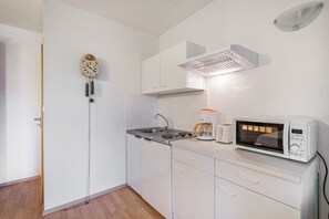 A small kitchen with white cabinets, a sink, a coffee maker, and a microwave. - Apartment "Heidi" with Mountain View, Private Garden and Wi-Fi (Rosenthal-Bielatal)