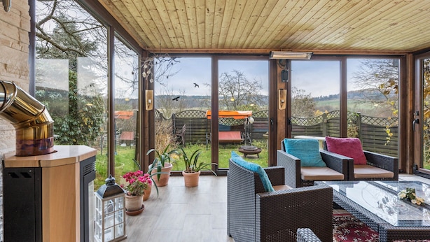 A covered patio with wicker furniture, a glass table, and a wood-burning stove. - Apartment "Heidi" with Mountain View, Private Garden and Wi-Fi (Rosenthal-Bielatal)