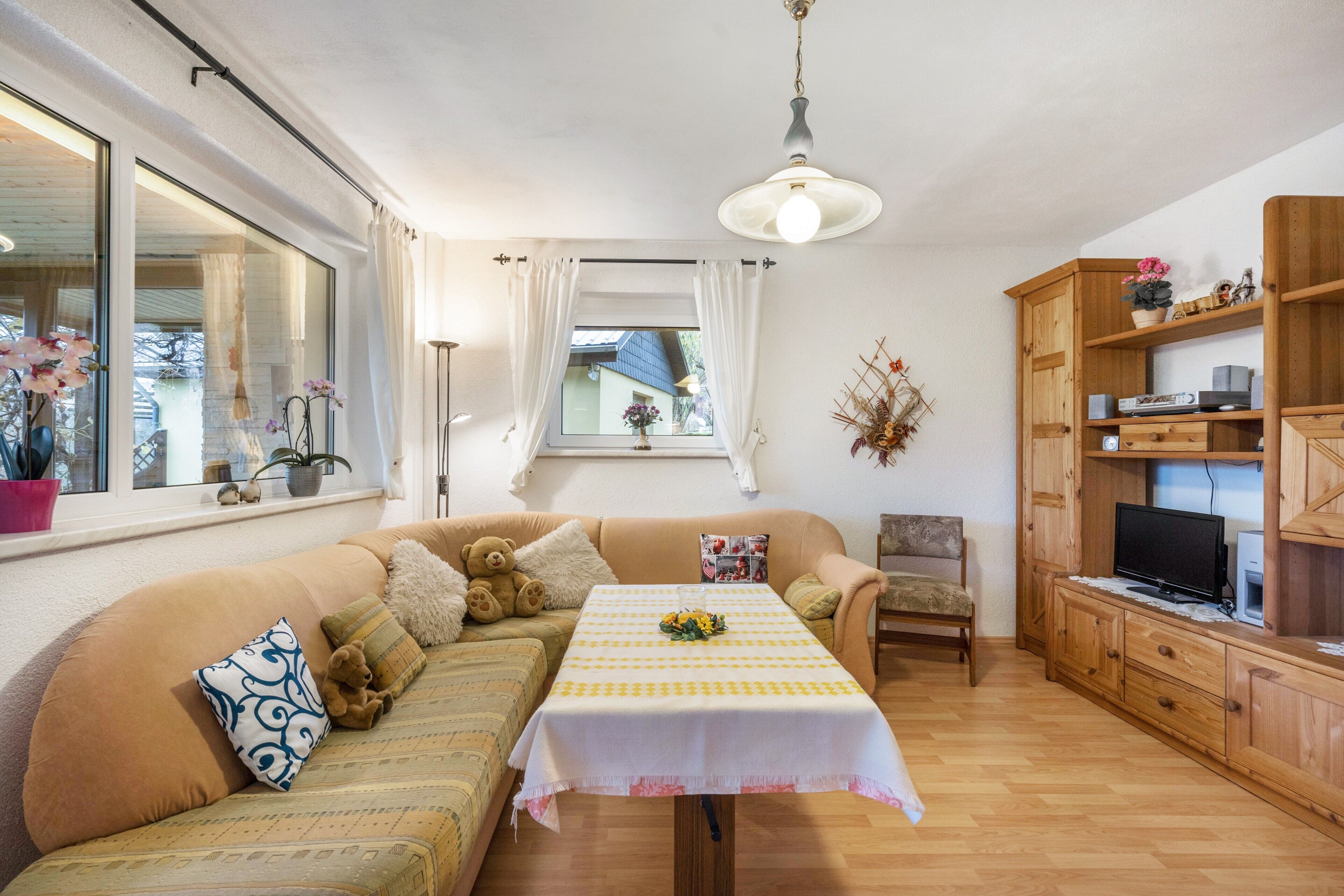A cozy living room with a sofa, a table, a television, and wooden cabinets.