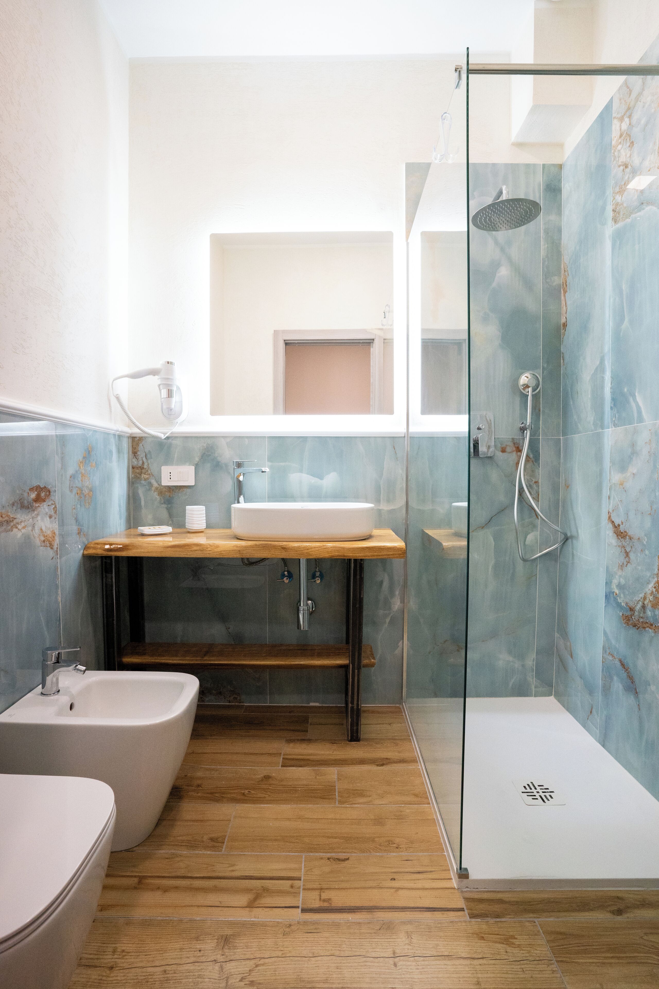 Un baño con tocador de madera, una bañera independiente y zona de ducha con mampara de vidrio.