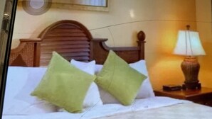 Een hotelkamer met een bed, kussens en een nachtkastje met een lamp.