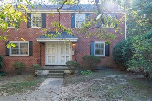 A brick house with a front door, a small porch, and a pathway leading to the door. - Walk to shops and dining, cozy and quiet 2BR (Raleigh)