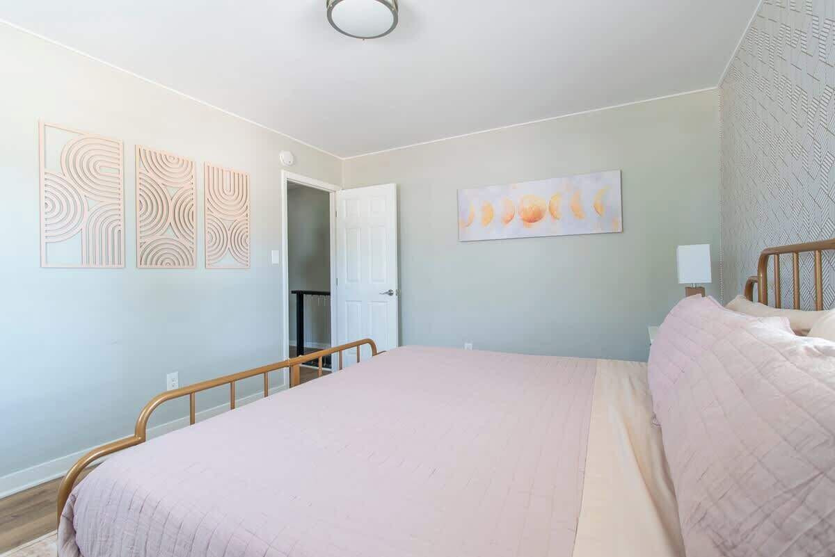 Une chambre à coucher avec un lit, une porte et des œuvres d’art mural.